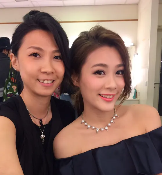 晚宴妝容：眼線配珊瑚粉紅色唇妝，頭髮挽起並留少量碎髮，模特兒身穿深藍色露肩裙，與化妝師在後台合照